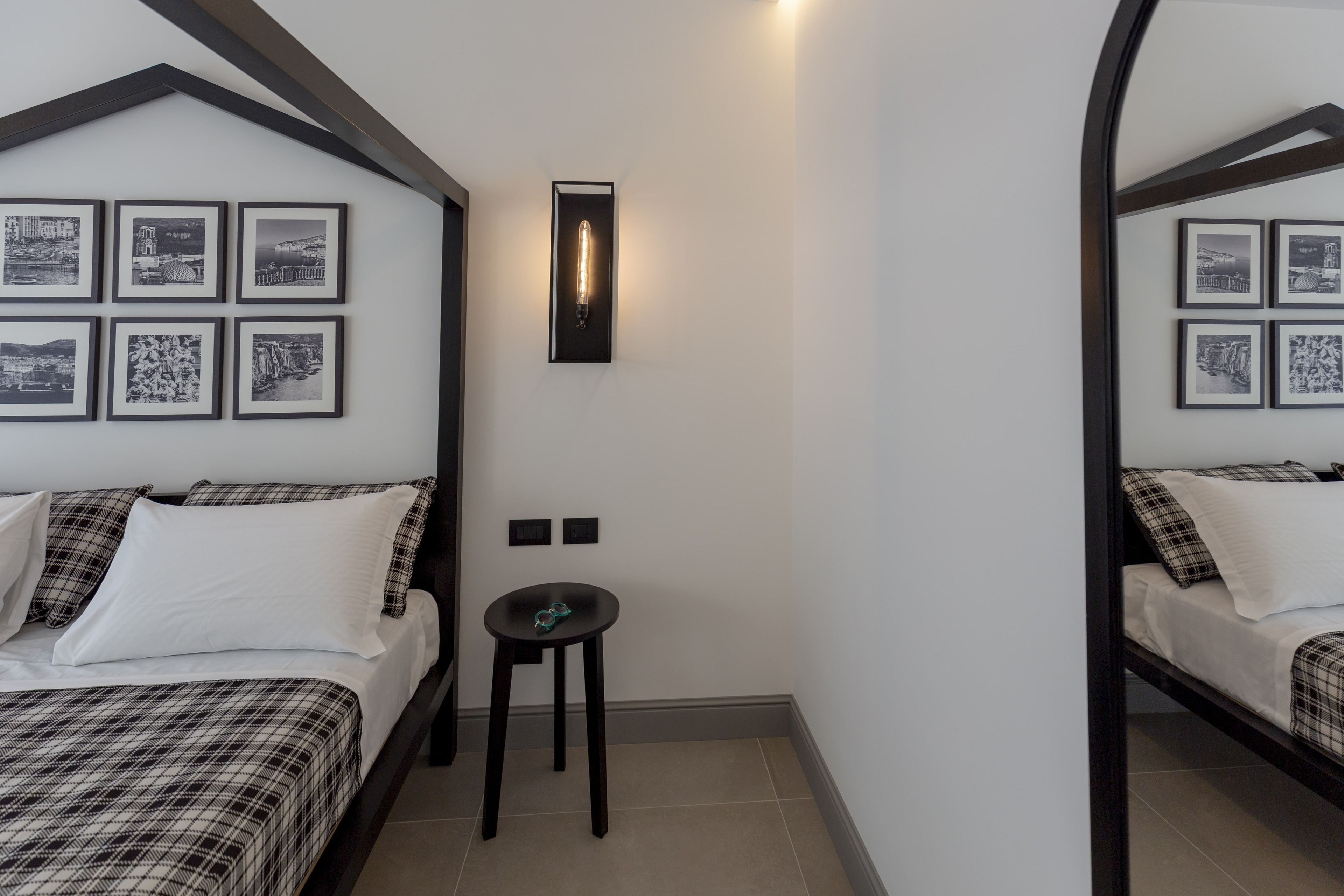Una habitación con dos camas, una mesita pequeña y una lámpara de pared.