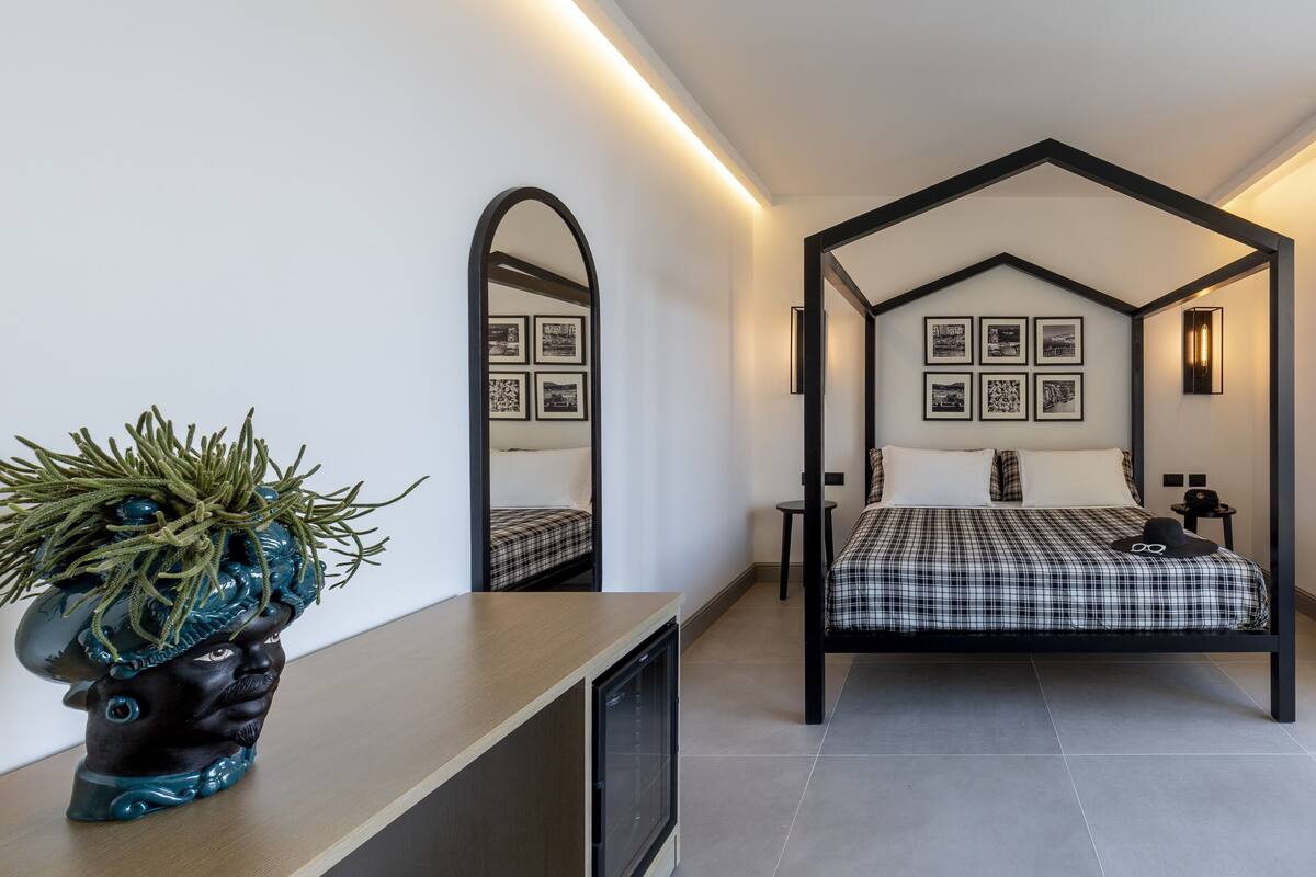 A modern bedroom with a bed, a mirror, and framed pictures on the wall.