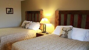Two twin beds with patterned bedding, a nightstand with a lamp, and a deer-themed pillow. - Crosby Lodge (Crosby)