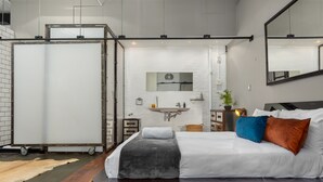 Ein modernes Schlafzimmer mit einem großen Bett, Holzboden, weißer Wand, Spiegel und weißem Schminktisch.