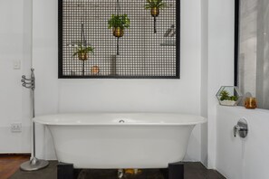 A modern bathroom with a freestanding bathtub, a wall-mounted plant display, and a small sink with a mirror.