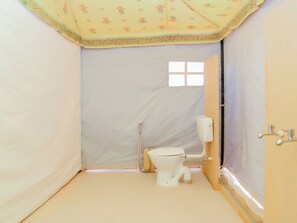 A small, enclosed bathroom with a toilet, a bidet, and a window.