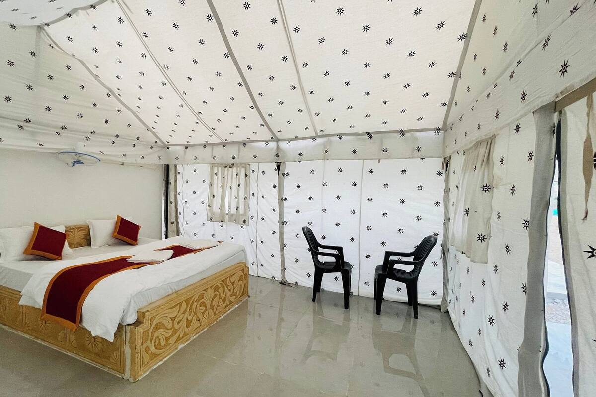 Een kamer met een bed, twee stoelen en een plafond met een sterrenpatroon.