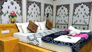A neatly made bed with patterned bedding, pillows, and a decorative vase with flowers. - Aroma Desert Safari Camp (Jaisalmer)