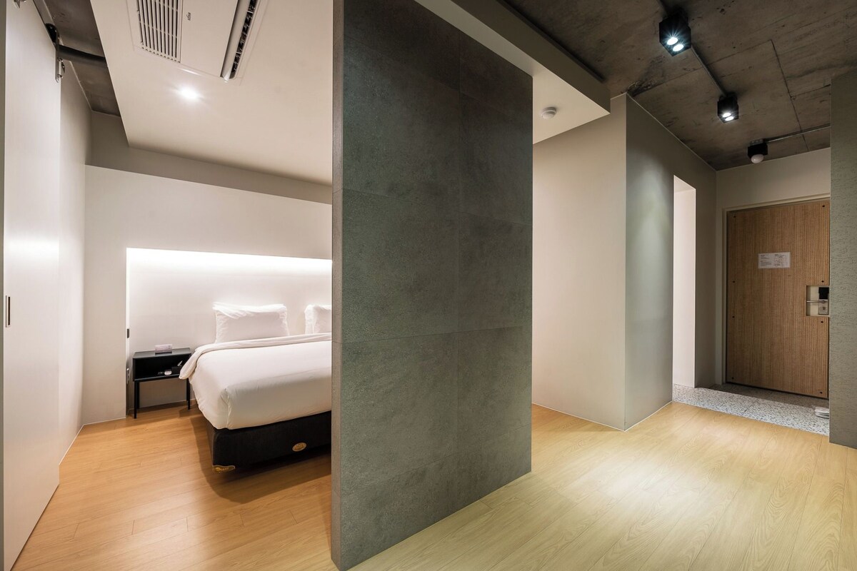 Una habitación de hotel moderna con cama, mesita de noche y armario.