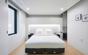 Een moderne slaapkamer met een groot bed, nachtkastjes, een raam en lijstwerken aan de muur.