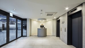 Un'accogliente area reception con banco informazioni, ampie finestre e due ascensori.