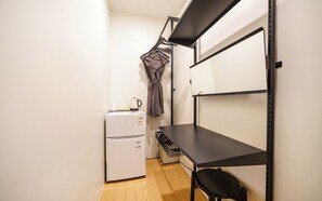 A compact kitchenette with a refrigerator, a sink, and a black chair. - Hotel Intro (Busan)