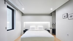 Una camera da letto moderna con un letto grande, un comodino, una lampada da parete e una finestra.