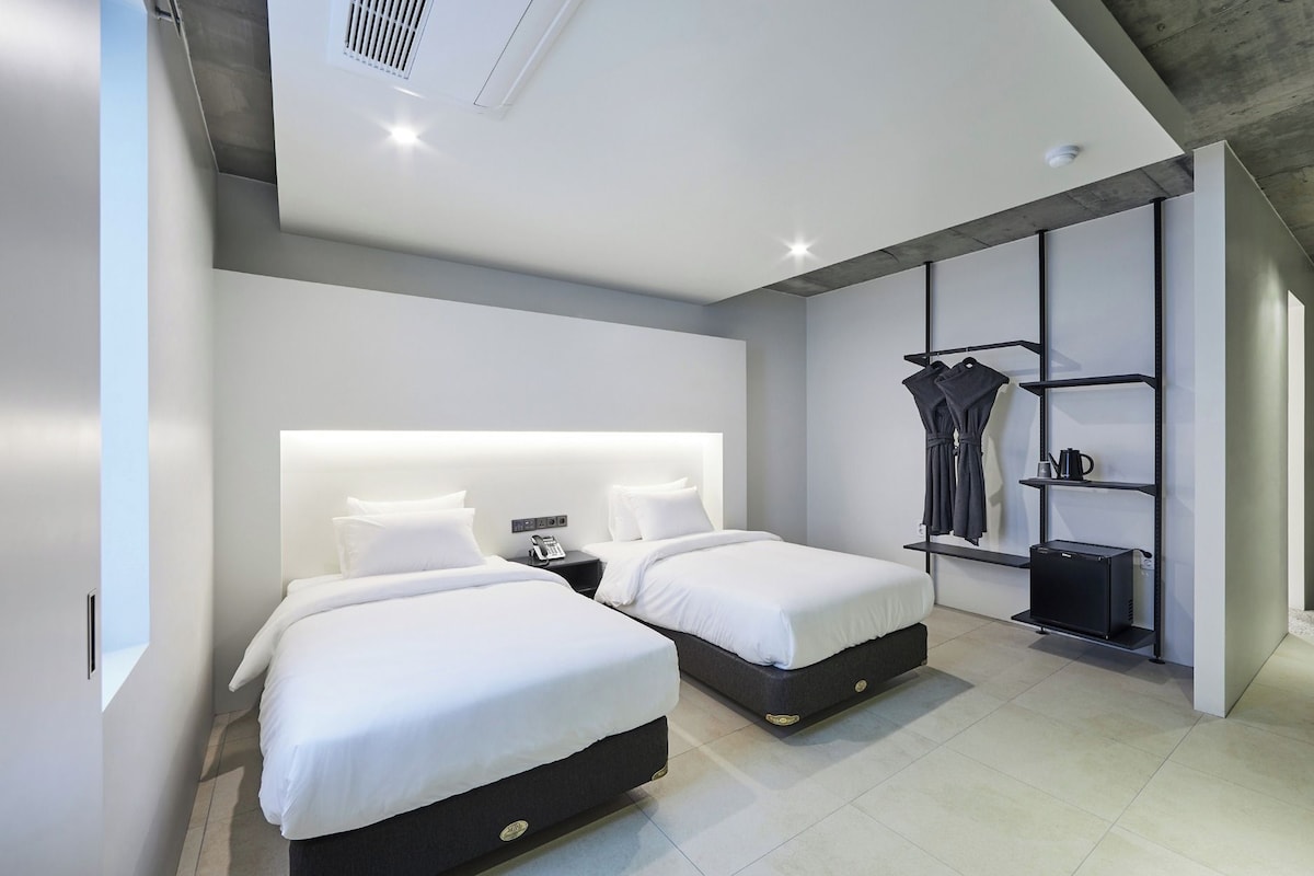 Habitación de hotel moderna con dos camas, un armario y una máquina de café.