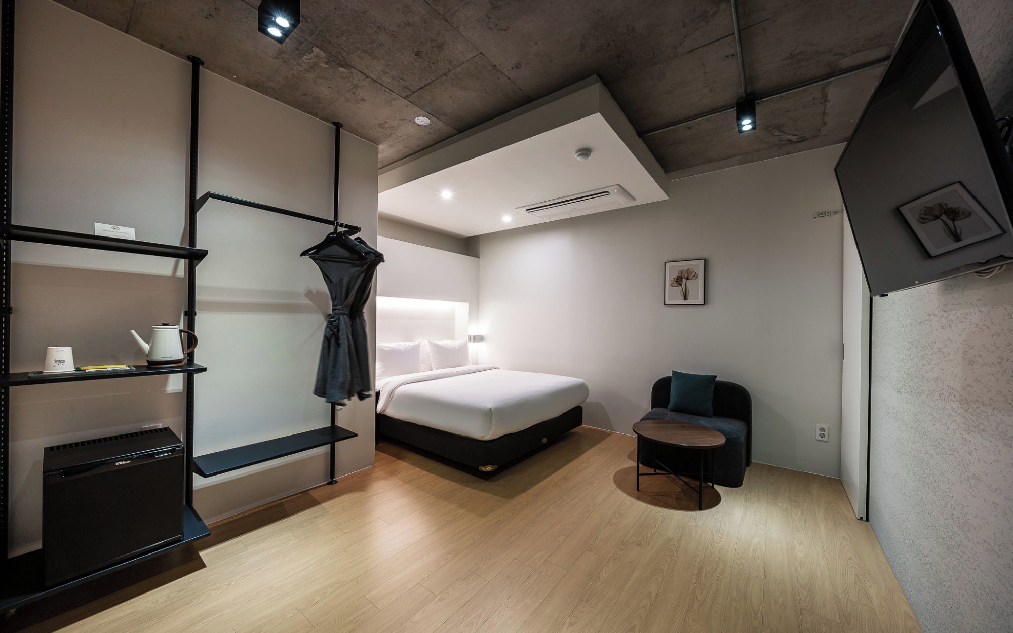 A modern hotel room with a bed, bedside table, and a small seating area.
