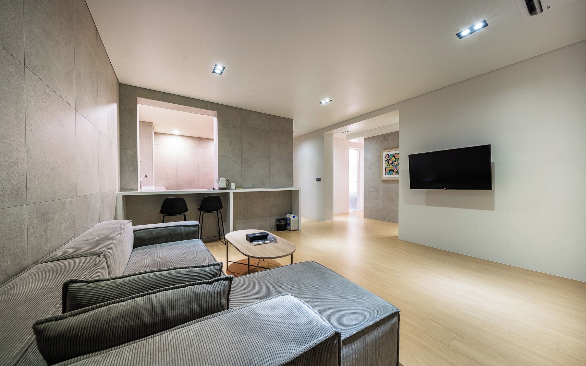 Una sala de estar moderna con un sofá, una mesa de centro y un televisor montado en la pared.