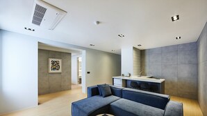 Un soggiorno moderno con un divano componibile, un tavolino in legno e un angolo cottura con lavello e pensili.