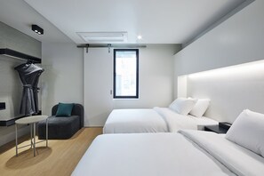 A modern hotel room with two beds, a small table, a bench, and a window with a view of the city. - Hotel Intro (Busan)