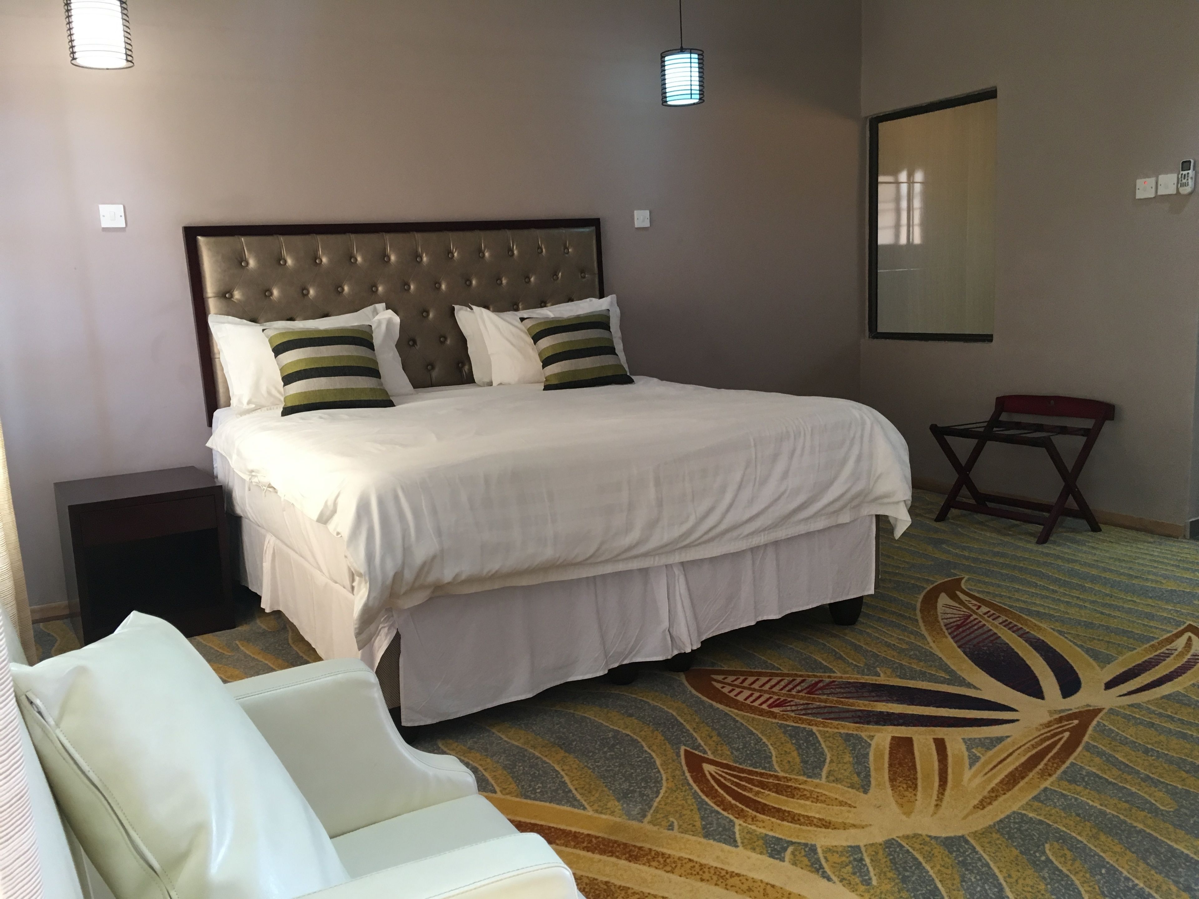 Une chambre d’hôtel avec un grand lit, une table de chevet, une chaise et une petite table.