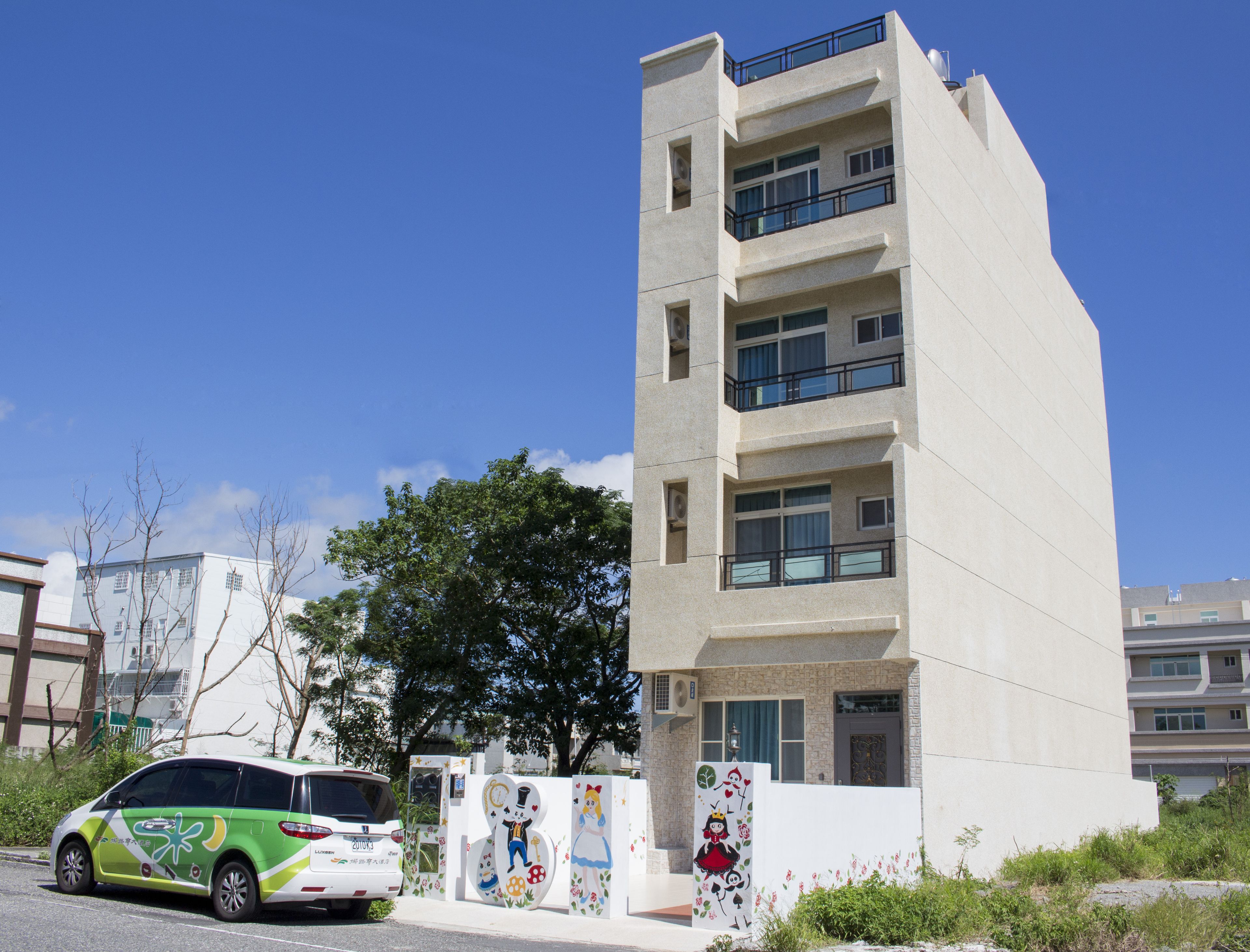 A modern building with multiple balconies and a car parked in front.