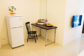 Uma pequena cozinha compacta com geladeira, mesa e uma cadeira.