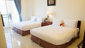 A hotel room with two beds, a nightstand with a lamp, a teddy bear, and a view of the balcony. - Na Na Ya Ji Bed and Breakfast (Taitung)