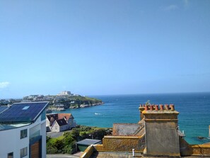 A coastal town with a prominent building on a hill, a marina, and residential buildings with solar panels.