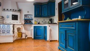 Una cocina con armarios azules, salpicadero de azulejos y suelo de baldosas.