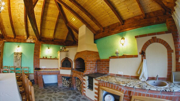 Una cocina rústica con horno de ladrillo, vigas de madera y un lavamanos.