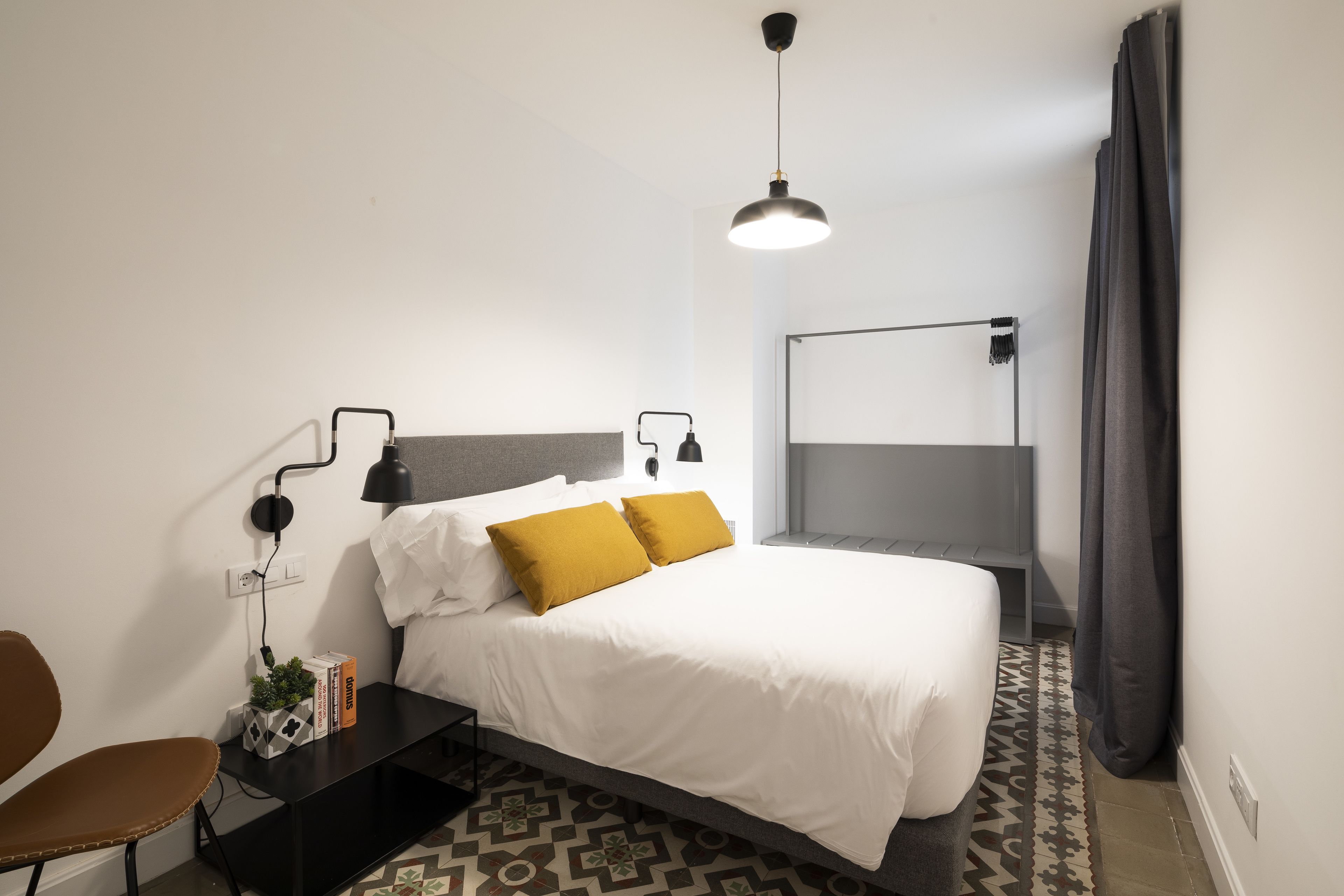 Una habitación de hotel moderna con cama, mesitas de noche, un escritorio y una silla.