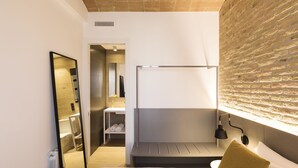 Ein modernes Hotelzimmer mit einem Bett, einem Spiegel, einem Kleiderschrank und einer Ziegelwand.
