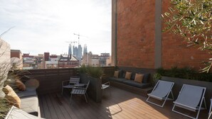 Eine Dachterrasse mit Sitzgelegenheiten, einem Tisch und Lounge-Stühlen.
