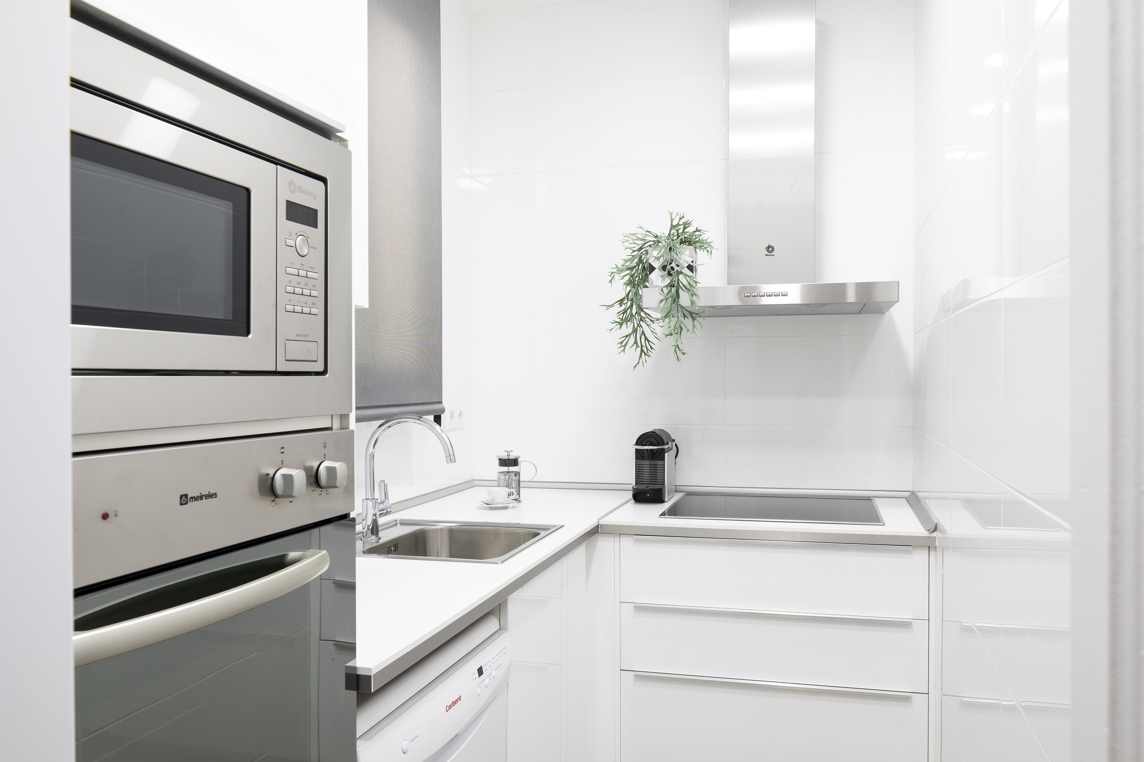 Une cuisine moderne équipée d’un four à micro-ondes, d’un four et d’une machine à café intégrés.