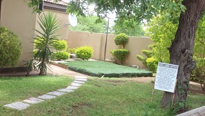 A well-maintained garden with a lawn, a stone pathway, and a signboard.