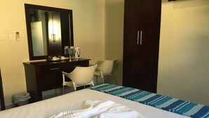 A hotel room with a bed, a desk, a chair, a wardrobe, and a mirror.