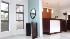 A reception area with a desk, a mirror, and a window.