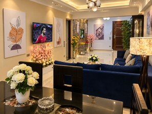 A modern living room with a blue sofa, a TV, artwork, and a fireplace.