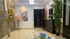 A spacious lobby with a stone wall, a large painting, and a variety of flowers. - Casa De Horyea  (Cairo)