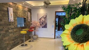 A modern interior with a stone wall, a large painting, a sunflower decoration, and a bar area with stools. - Casa De Horyea  (Cairo)