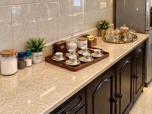 Un comptoir de cuisine avec un plateau contenant des tasses à thé, du sucre et des boîtes de thé Lipton.