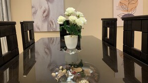 A dining table with a white vase of white flowers, surrounded by black chairs. - Casa De Horyea  (Cairo)