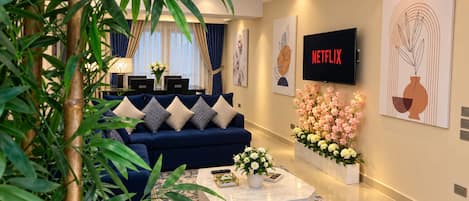 Un saló modern amb un sofà blau, una taula de centre i una televisió que mostra 'NETFLIX'.