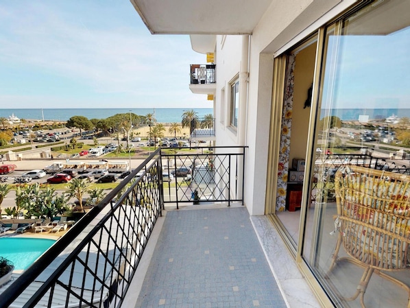 A balcony with a view of a parking lot and a swimming pool.