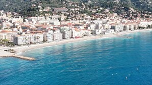 Una ciudad costera con playa, edificios y montañas al fondo.