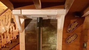 Ein Kaminofen in einem Blockhauszimmer mit einer Holztreppe und einer Kaminwand.