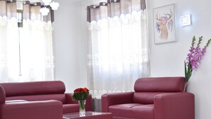 Ein modernes Wohnzimmer mit zwei roten Sofas, einem Couchtisch mit Blumenvase und einem Wandbild von einem Reh.