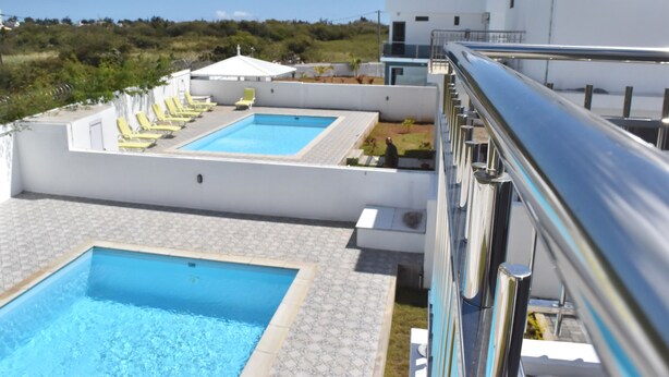 Ein Poolbereich auf dem Dach mit zwei Pools und gelben Liegestühlen.