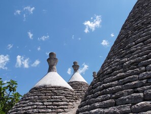 A stone tower with conical roofs against a clear blue sky. - Trulli sotto La Cupa (Martina Franca)