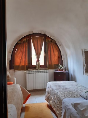 Relax in this serene space with a high, arched window, a comfortable bed, and a cozy reading nook.
