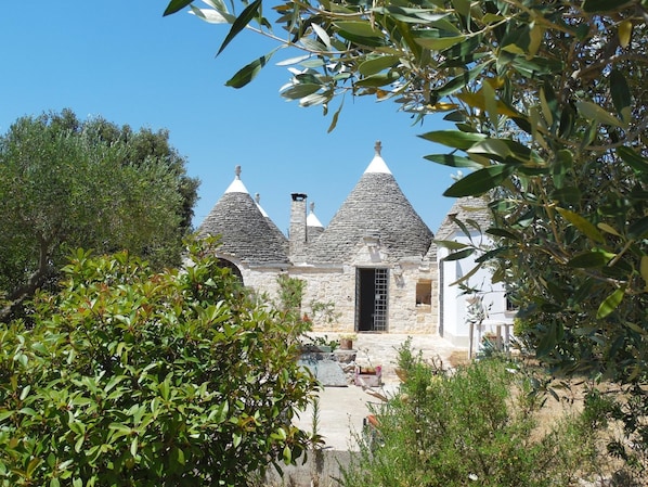 Traditional stone building with a rustic, Mediterranean style, set amidst lush greenery.