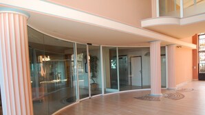 A spacious lobby with a curved glass wall, a potted plant, and a patterned floor. - Stunning 3BR Apartment with Sea View, Terrace, and Garage in Menton (Menton)