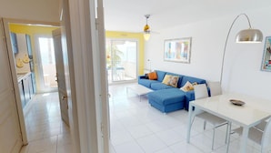 A modern living room with a blue sofa, a dining table, and a ceiling fan. - Stunning 3BR Apartment with Sea View, Terrace, and Garage in Menton (Menton)