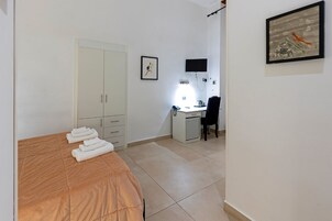 Un dormitorio con cama, escritorio, silla, armario y un cuadro en la pared.