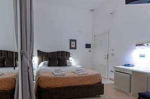 Een slaapkamer met twee bedden, een bureau en een kledingkast.
